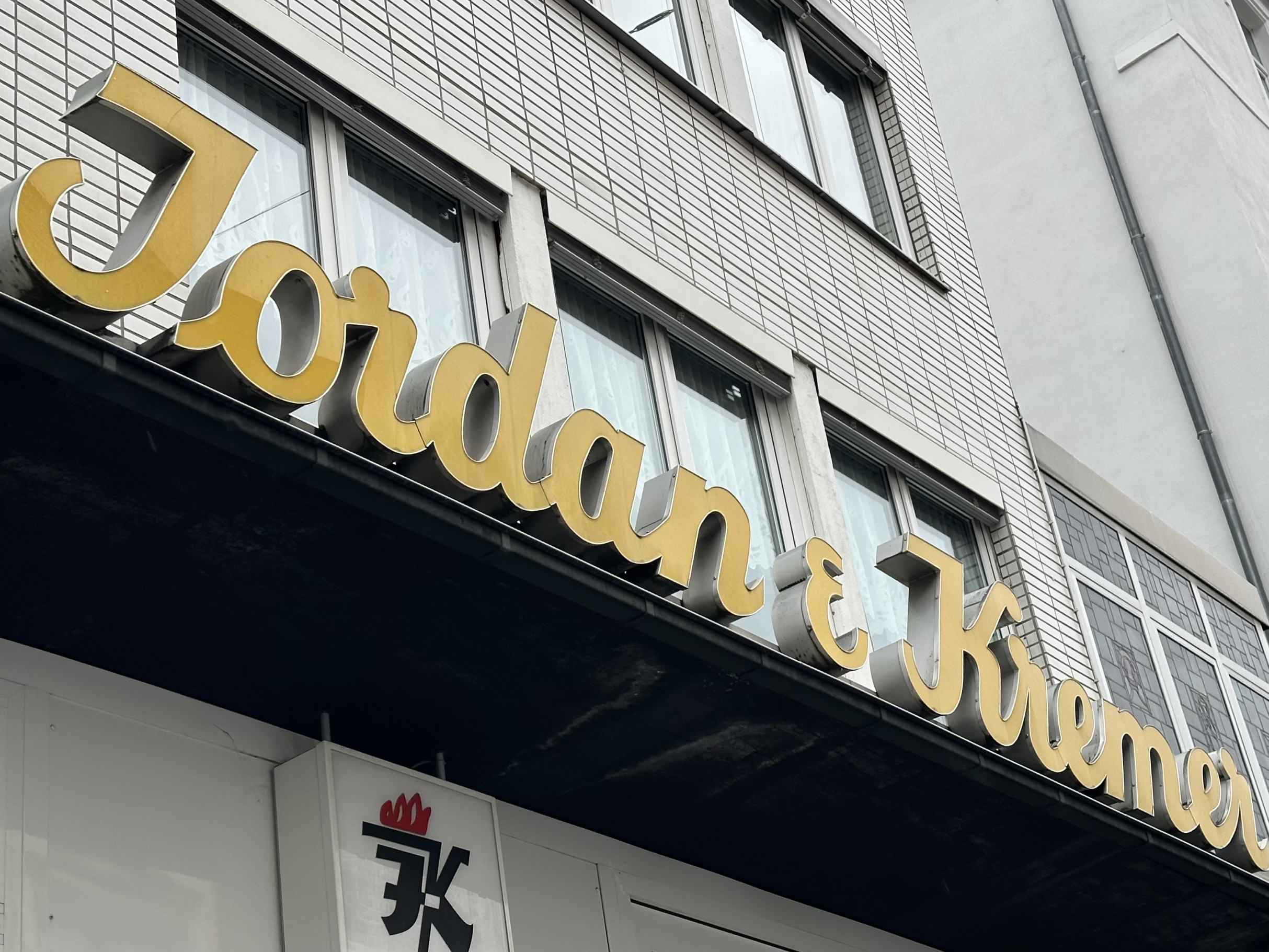 Fassade mit Schriftzug über dem Schaufenster der Firma Jordan & Kremer im Sandweg